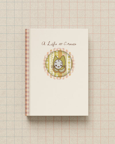 Notebook with a decorative cover featuring Mamoo the cat and text on a grid background