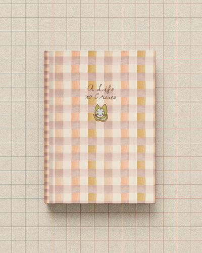 A Life to Create journal with a coral gingham cover and minimal illustration of Mamoo the cat